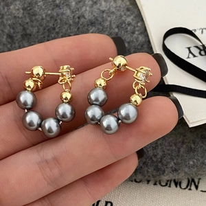 Detail of U-shaped gold earrings with grey pearls and sparkling zircon accents