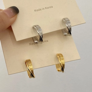 Détail de boucles d'oreilles superposées dorées et argentées avec fini rayé texturé