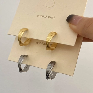 Détail de boucles d'oreilles créoles en C torsadées multicouches en métal mat doré et argent