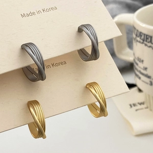 Détail de boucles d'oreilles multicouches croisées au fini mat doré et argent