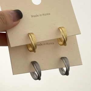 Détail de boucles d'oreilles créoles texturées en finitions or et argent