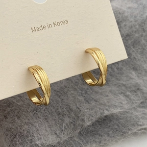 Macro shot of gold layered hoop earrings on jewelry card with textured background