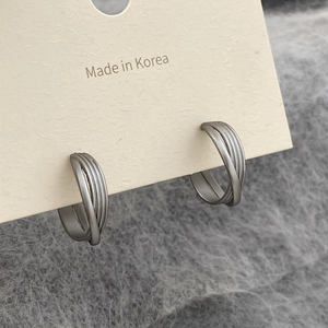 Macro detail of silver layered metal hoop earrings with a matte brushed texture