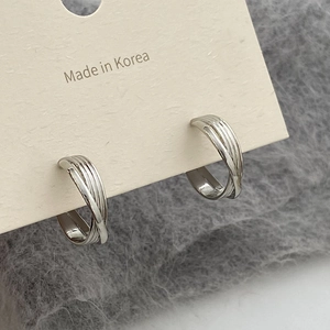Vue macro de boucles d'oreilles créoles en argent avec texture métallique torsadée