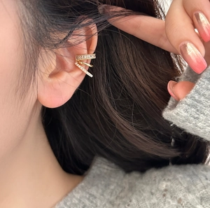 Gros plan d'un ear cuff triple rangée en or avec perles et zircons sur l'oreille