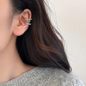 Gros plan d'une boucle d'oreille à trois couches avec perles et zircons sur l'oreille