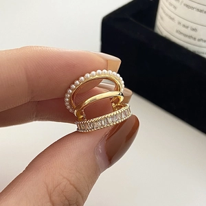 Détail de bagues d'oreille dorées avec perles, anneau poli et oxydes de zirconium baguettes