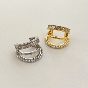 Détail de boucles d'oreilles ear cuffs dorées et argentées avec zircons et perles blanches