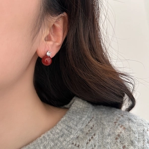 French luxury red pearl stud earrings with zircon accents on a female model