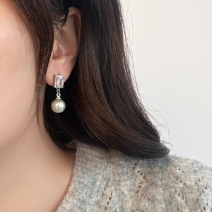 Detail of elegant grey pearl drop earrings with rectangular zircon on female model