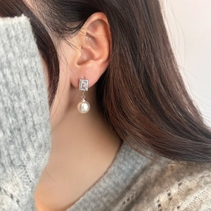 Close-up of elegant square zircon stud earrings with white pearl drop on model