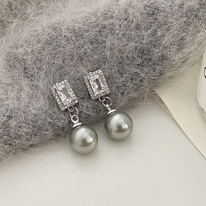 Detail shot of grey pearl drop earrings with sparkling zircons on plush grey fabric
