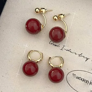 Detail view of 14mm red pearl earrings with size and weight measurements on canvas