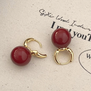 Close-up of vintage gold hoop earrings featuring polished burgundy red enamel beads