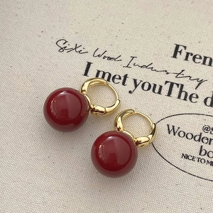 Detailed close-up of French vintage gold hoops with glossy dark red pearl pendants