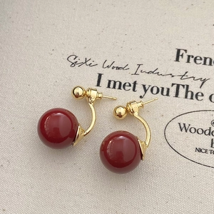 Macro view of French retro red pearl earrings with elegant gold-plated metal hooks