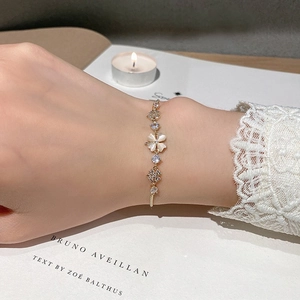 Close-up of elegant gold flower bracelet with cat eye stone petals on female wrist