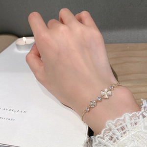 Detail of clover bracelet with cat-eye petals and zircons on gold chain for women