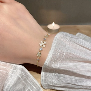 Macro detail of elegant clover bracelet with cat-eye stone petals and zircons on wrist