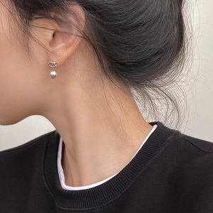 Détail des boucles d'oreilles nœud en argent avec perles portées par un mannequin chic