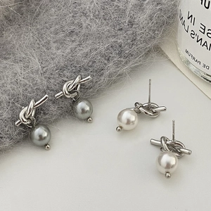 Gros plan de boucles d'oreilles perles avec nœud argenté en gris et blanc élégant