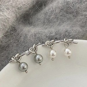 Gros plan de boucles d'oreilles nœud et perle en argent avec perles grises et blanches