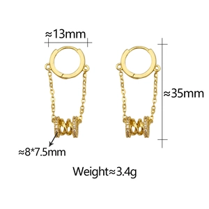 Detail of gold hoop earrings with hanging spiral cylinder pendants and zircon inlays