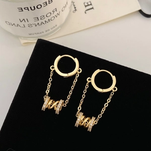 Detail of gold chain earrings with sparkling zircon cylinders on a black velvet display