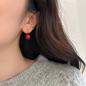 Élégantes boucles d'oreilles perles rouges portées par un mannequin en gros plan de profil