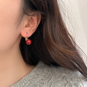 Gros plan de boucles d'oreilles perles rouges avec crochets dorés sur un mannequin