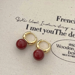 Détail de boucles d'oreilles vintage en or avec perles rouge foncé sur toile
