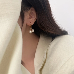 Detail of double pearl drop earrings in gold finish worn by model for elegant style