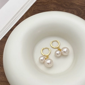 Elegant gold drop earrings featuring double shell pearls on a minimalist hoop design