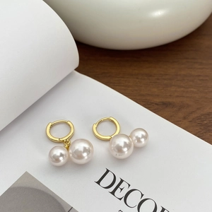 Korean style double pearl drop earrings with gold hoops on white book background