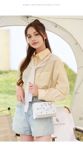 Détail de la broderie florale rose sur un sac blanc avec bandoulière chaîne dorée