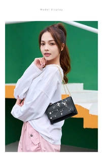 Mannequin portant un sac bandoulière noir avec broderie florale et chaîne dorée