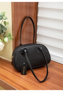 Close-up of black lychee grain texture and gold zipper on a chic leather handbag