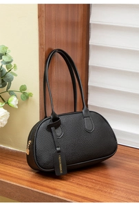 Detail of black lychee texture leather handbag with Fashion & Bags decorative tag