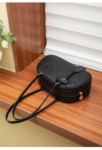 Detailed view of black lychee grain leather texture with gold zipper and fashion tag