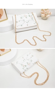 Gros plan sur la broderie florale rose et la chaîne dorée du sac à bandoulière blanc