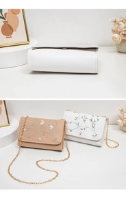 Détails de broderie florale sur des sacs bandoulière beige et blanc avec chaîne dorée