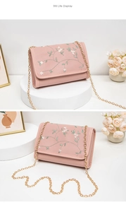 Vue détaillée des broderies florales et de la chaîne dorée du sac à main rose