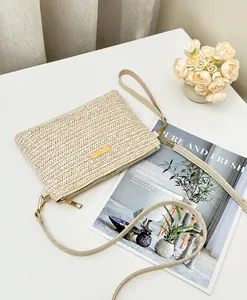 Détail du sac bandoulière en paille tressée crème avec plaque dorée et fermeture éclair