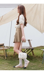 Detailed view of floral embroidery and butterfly motif on white crossbody bag