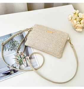 Détail du sac enveloppe en paille tressée beige avec plaque dorée et bandoulière crème
