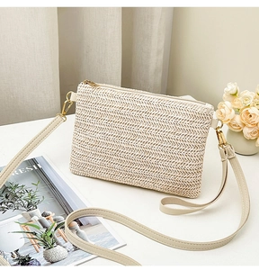 Détail d'un sac bandoulière en paille tressée beige avec fermeture éclair dorée