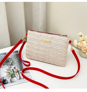 Détail du sac à bandoulière en paille tressée avec bandoulière en cuir rouge