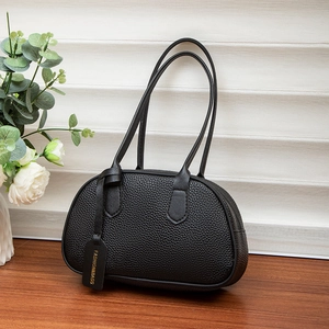 Litchi pattern black semi-circular underarm bag on a wooden table with flowers