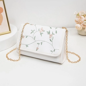 Sac bandoulière blanc avec broderie florale et chaîne dorée, style minimaliste