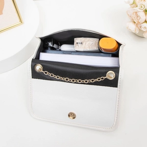 Sac bandoulière noir et blanc à chaîne dorée montrant la capacité de rangement intérieur